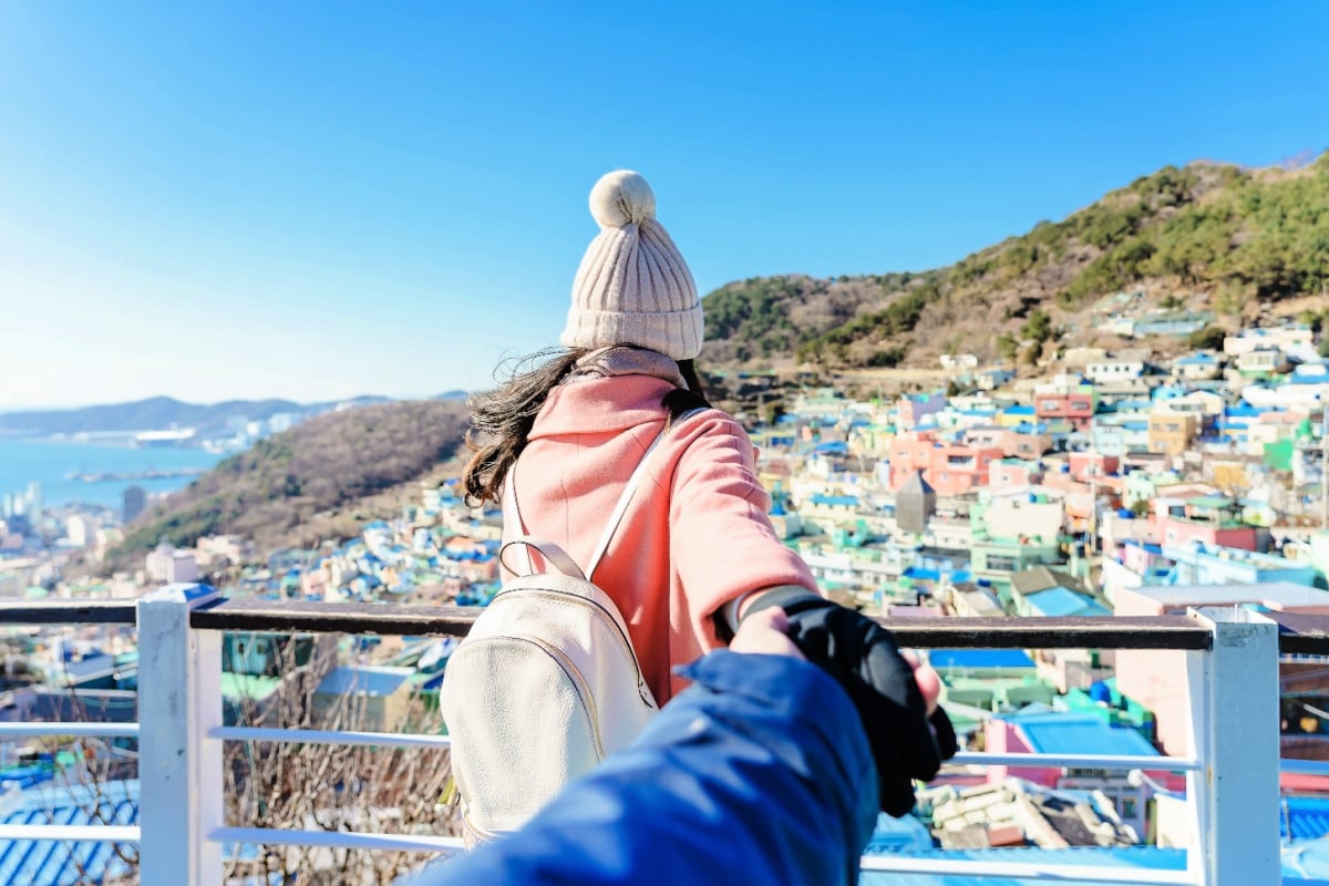 Traveling together. Follow me, Young woman leading boyfriend to the gamcheon Culture Village located at Busan, South Korea