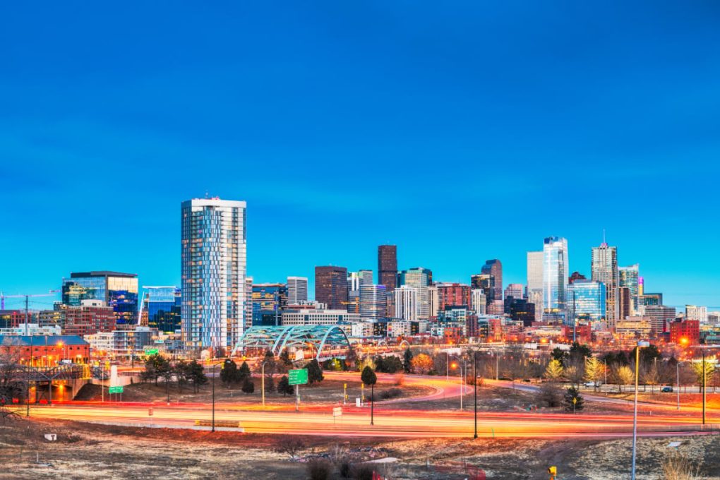 city skyline of denver at dusk with light trails from cars in foreground